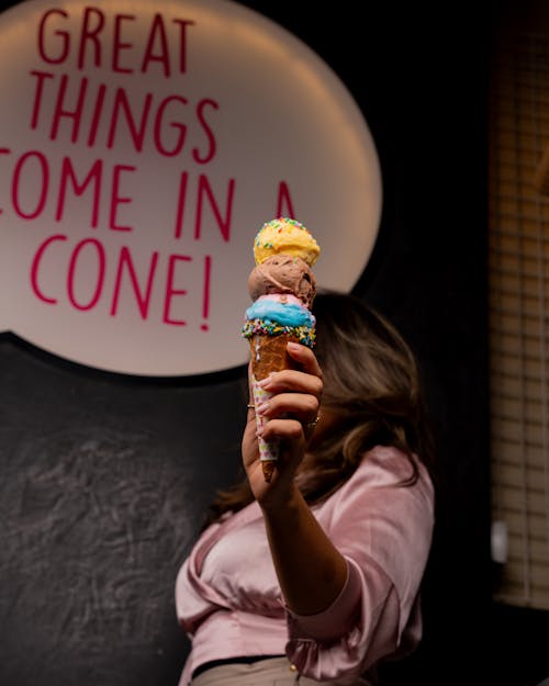 A woman holding an ice cream cone with the words great things come in a cone