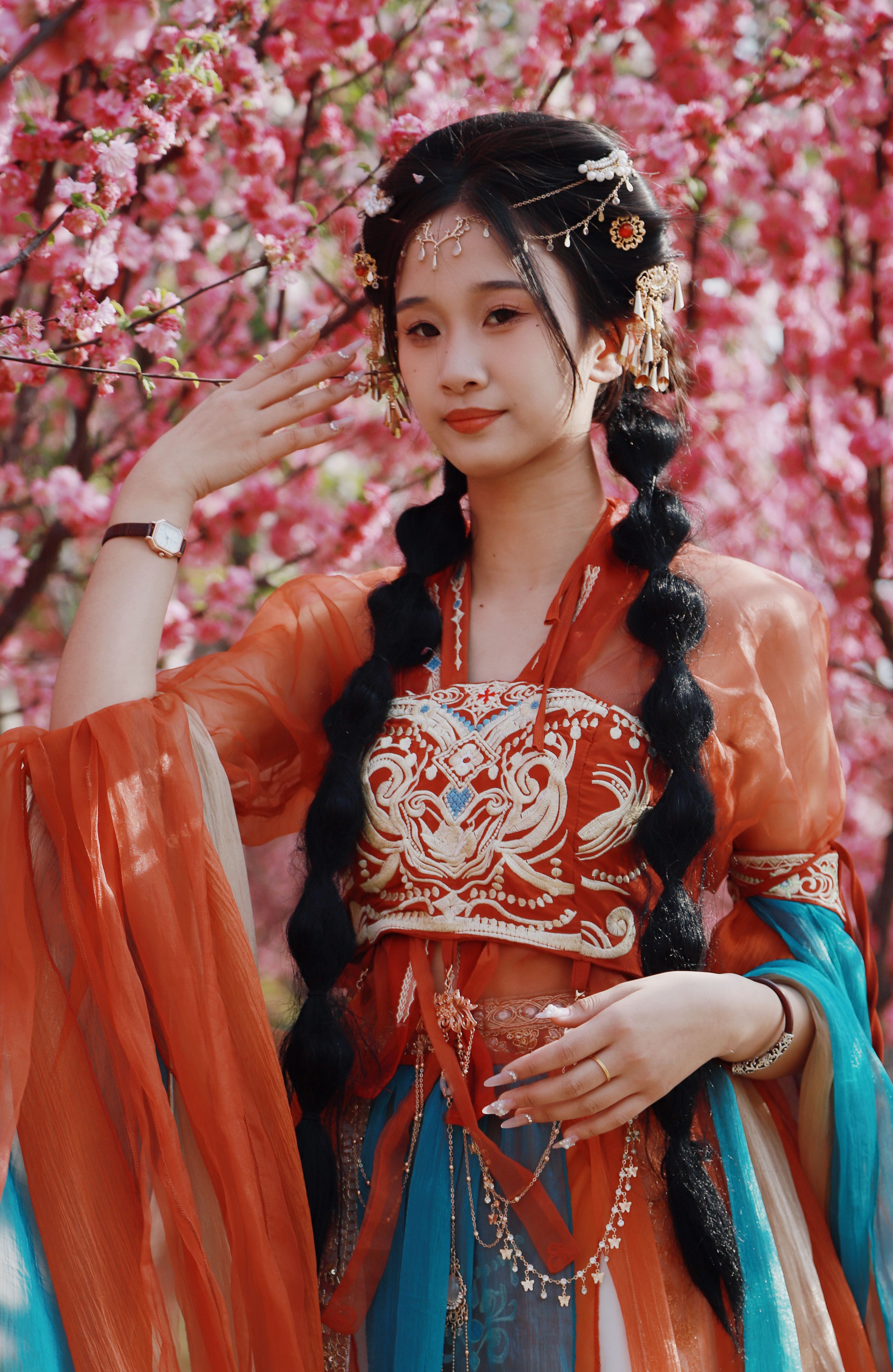 A woman in traditional Hanfu stands gracefully among the vibrant spring blossoms, showcasing cultural elegance.