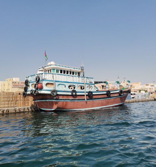 Free A traditional wooden boat moored in Dubai harbor under a clear blue sky. Stock Photo