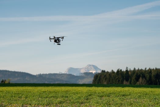Drone flying over lush green farmland with mountain backdrop in Upper Austria.