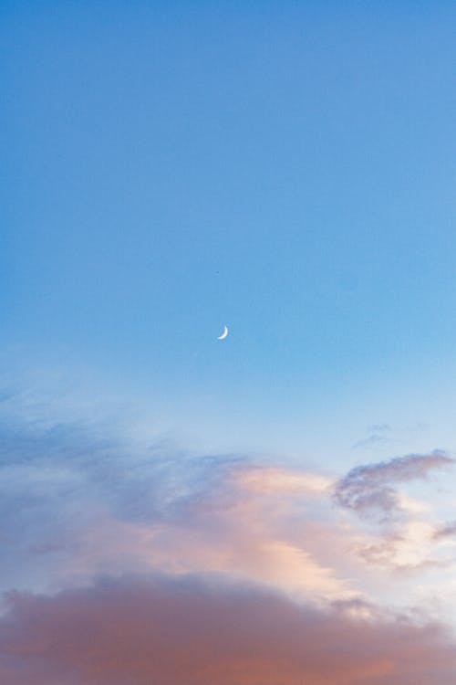 A moon and clouds in the sky at sunset