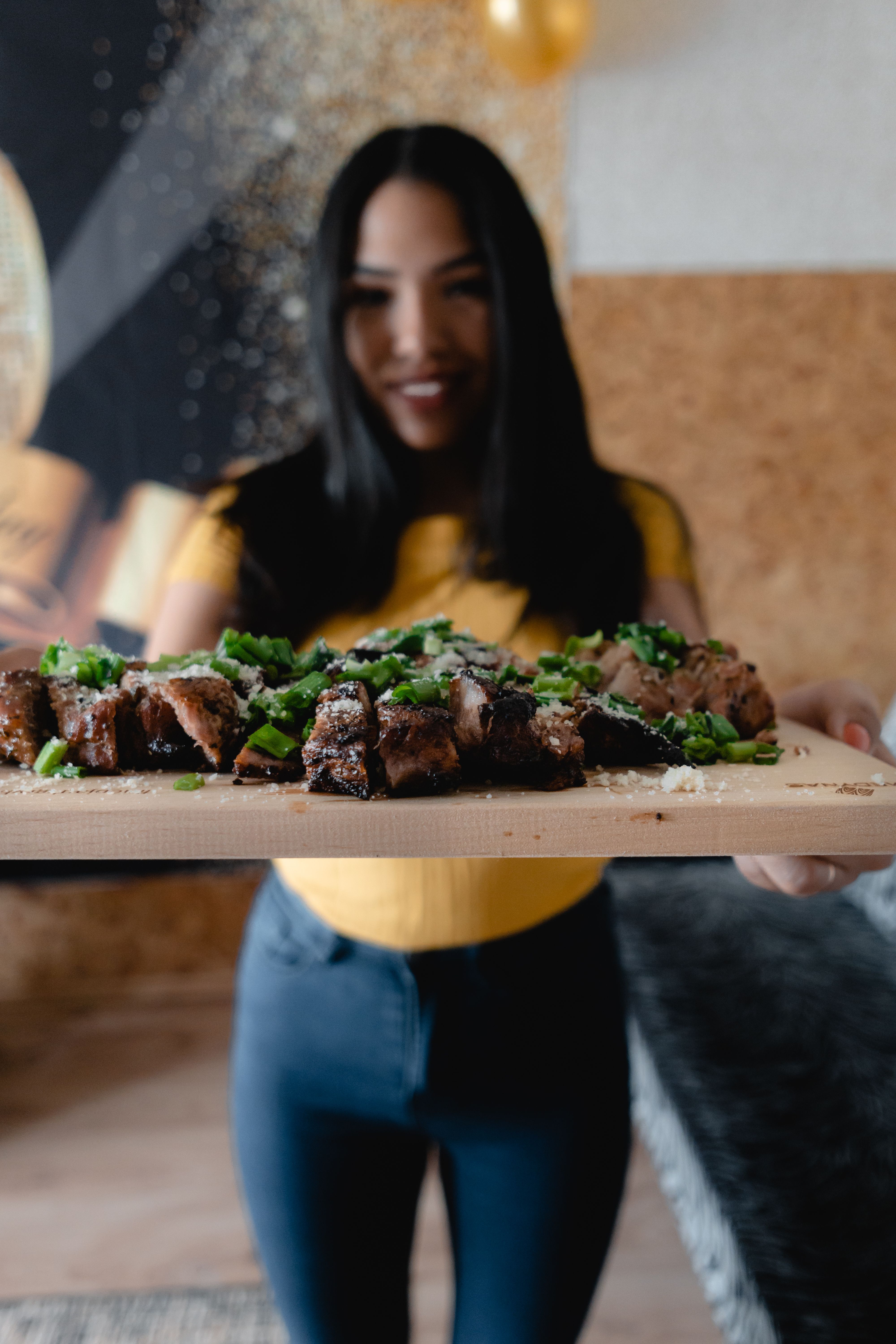 A woman presenting a mouthwatering grilled steak garnished with fresh greens, perfect for a food lover.
