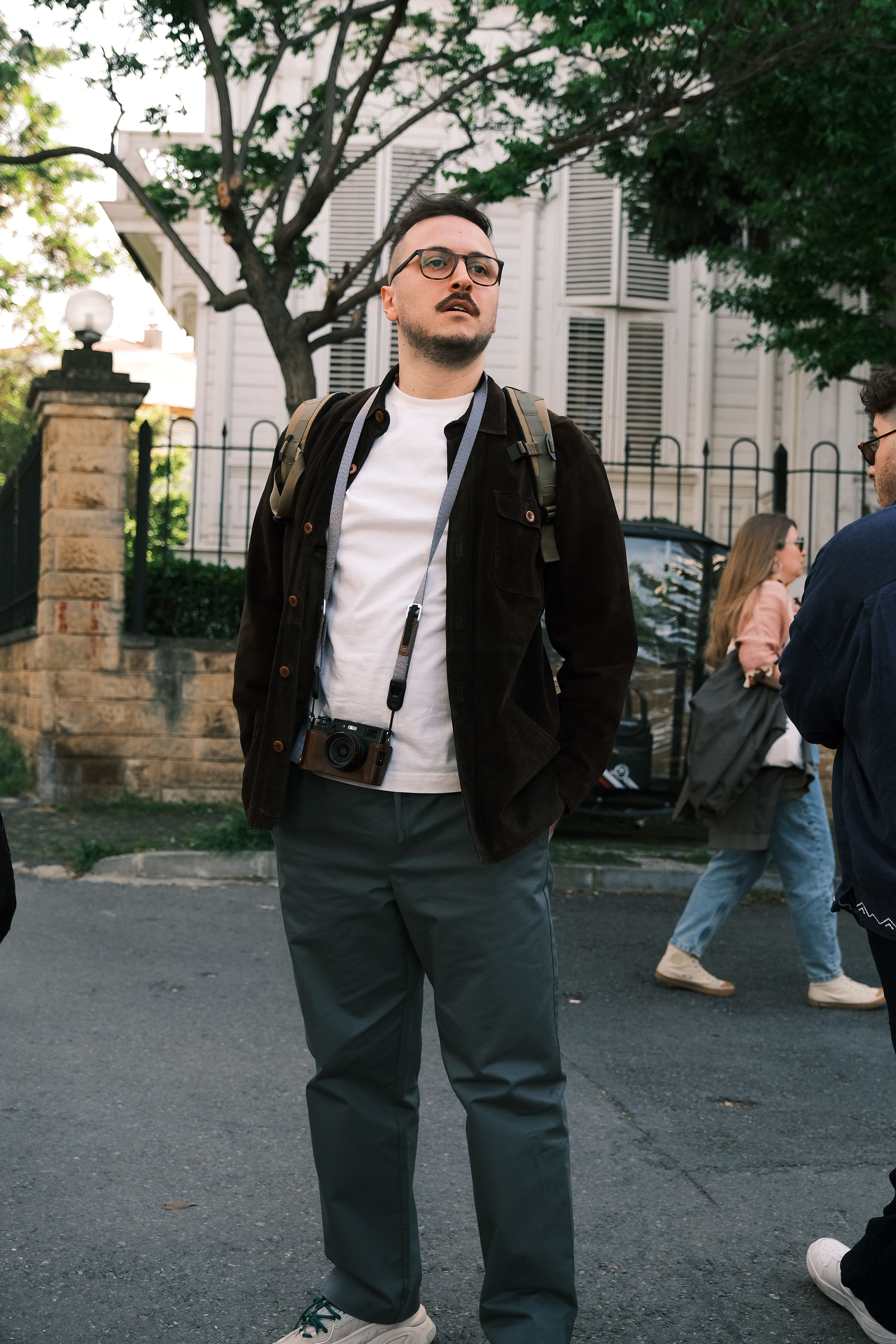 Portrait of a man with a camera on a city street. Urban backdrop and casual style enhance the urban vibe.