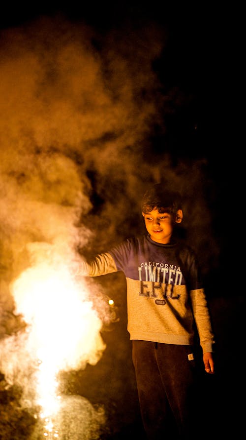 A boy is holding a firework in the dark