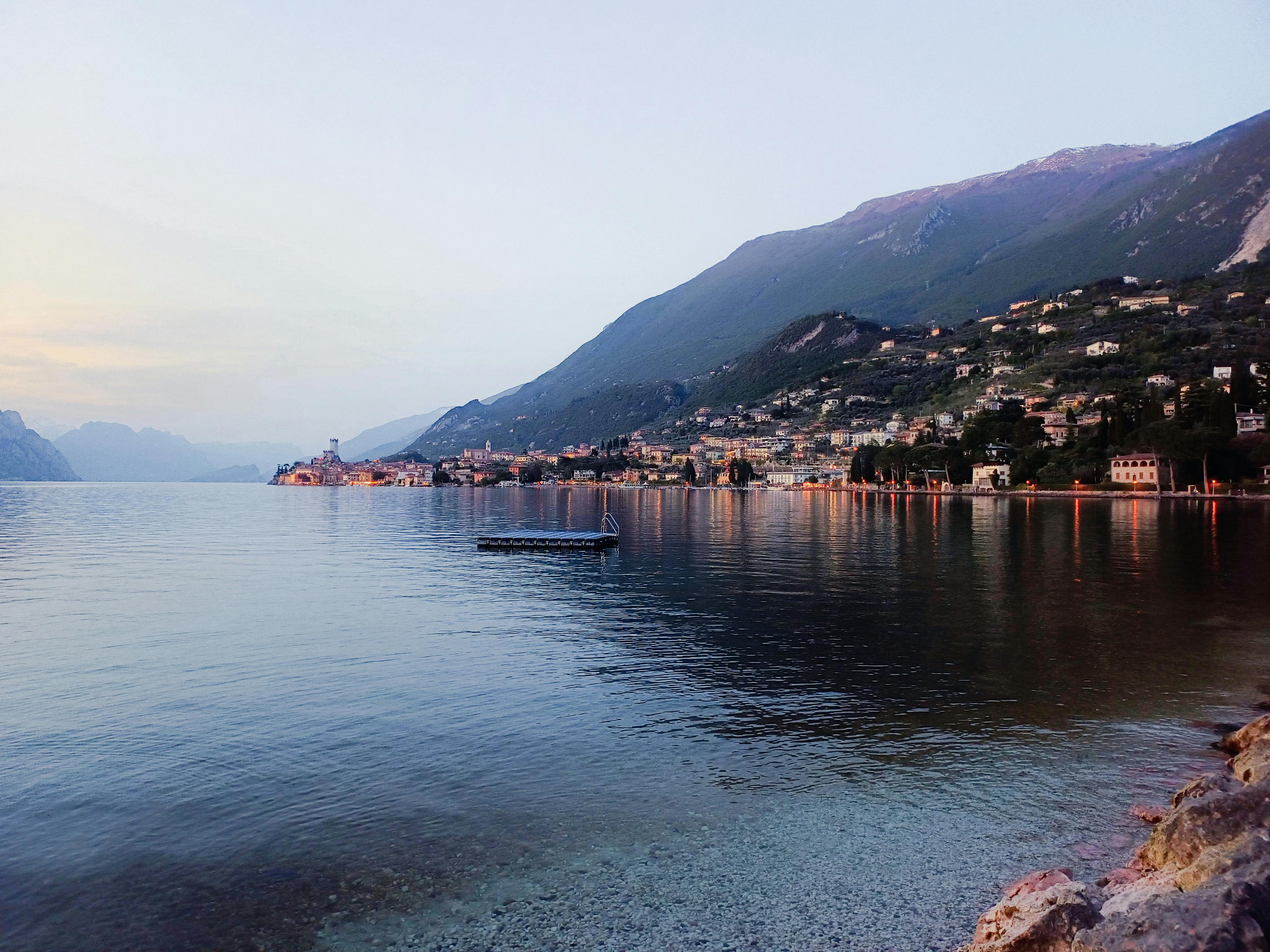 Serene view of Malcesine, Italy, with lake and mountains at dusk. Ideal for travel inspiration.