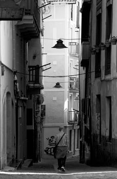 A lone figure walks down a narrow alley in Pasajes, Spain.