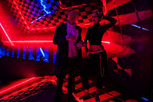 Two people standing in front of a neon light