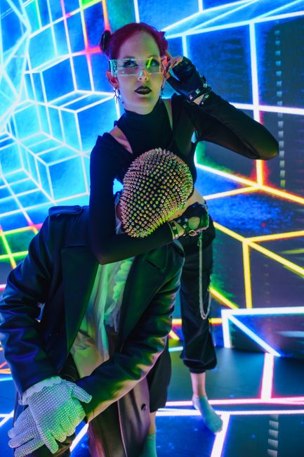 Dynamic duo perform in neon-lit club with futuristic style.