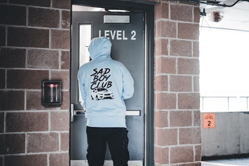 A man in a hoodie standing in front of a door