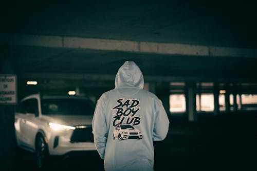 A man standing in a parking garage wearing a hoodie with the words bad boy club