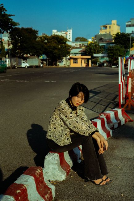 Stylish woman sitting in urban setting with striped red and white curb.
