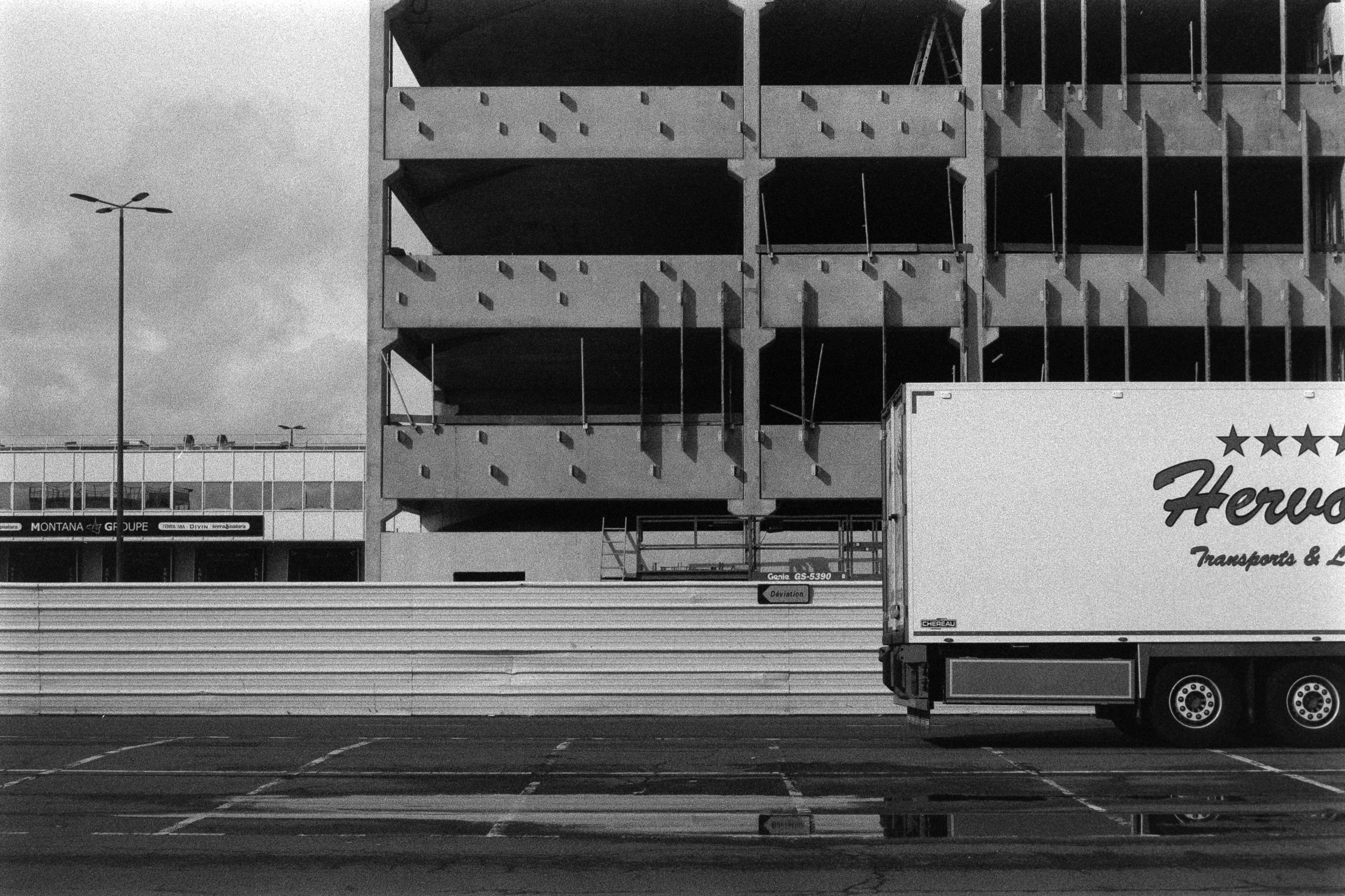 Black and white photo of a truck and building construction in a French urban area.