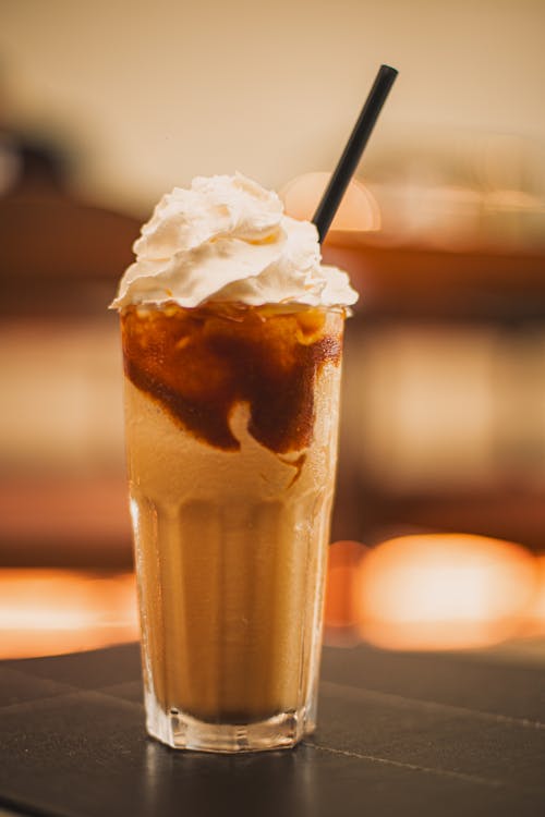 A glass of iced coffee with whipped cream and caramel