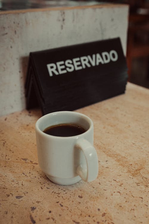A cup of coffee sits on a table next to a sign that says reservado