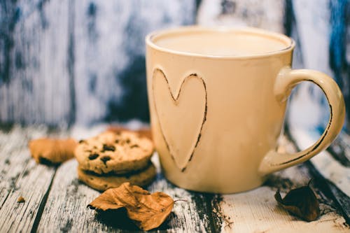 Tazza Di Cuore In Ceramica Beige Con Caffè Accanto Al Cibo Biscotto