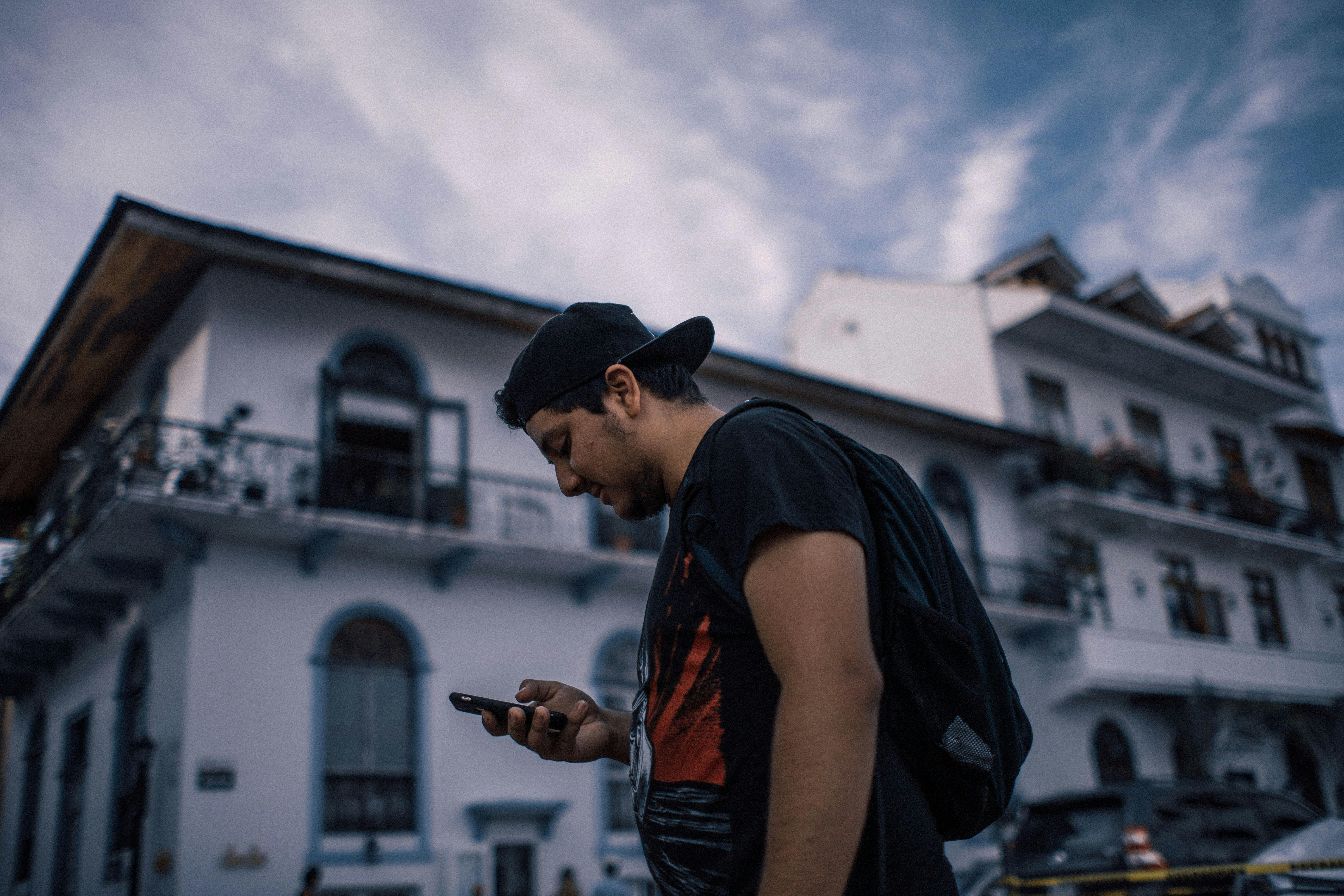 Side View Photo of Man in Black T-shirt Using Smartphone