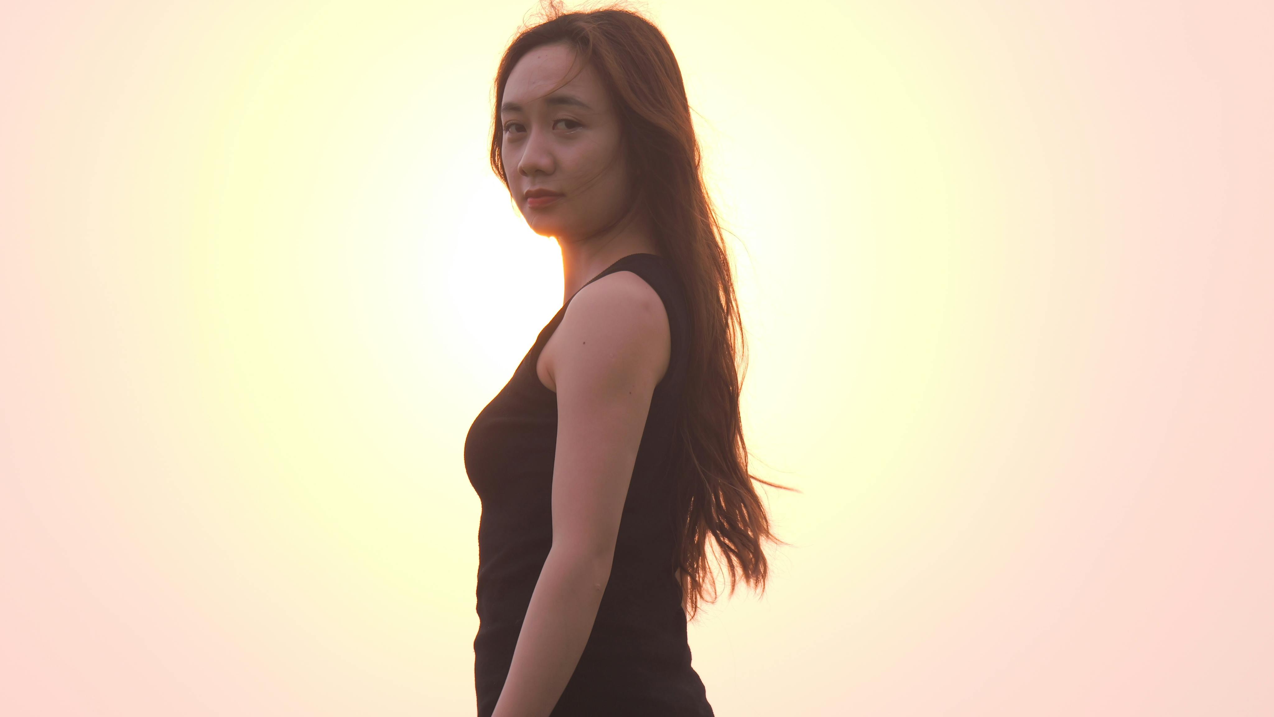 Portrait of an elegant woman standing against the warm hues of sunset, capturing grace and tranquility.