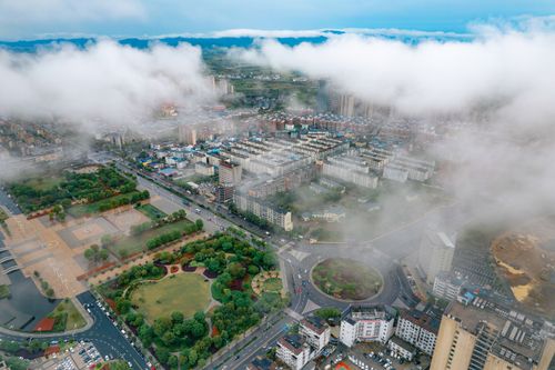 Free Aerial view of Jiujiang City, China, featuring a prominent roundabout and urban landscape partially covered by clouds. Stock Photo