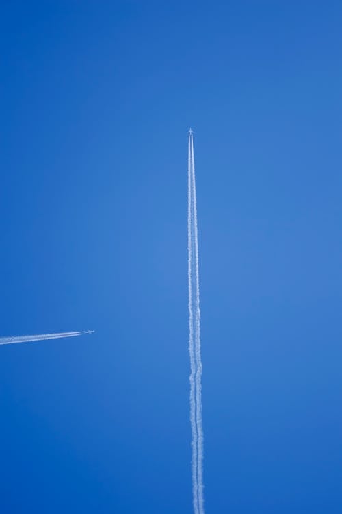 A jetliner flying in the sky with two contrails