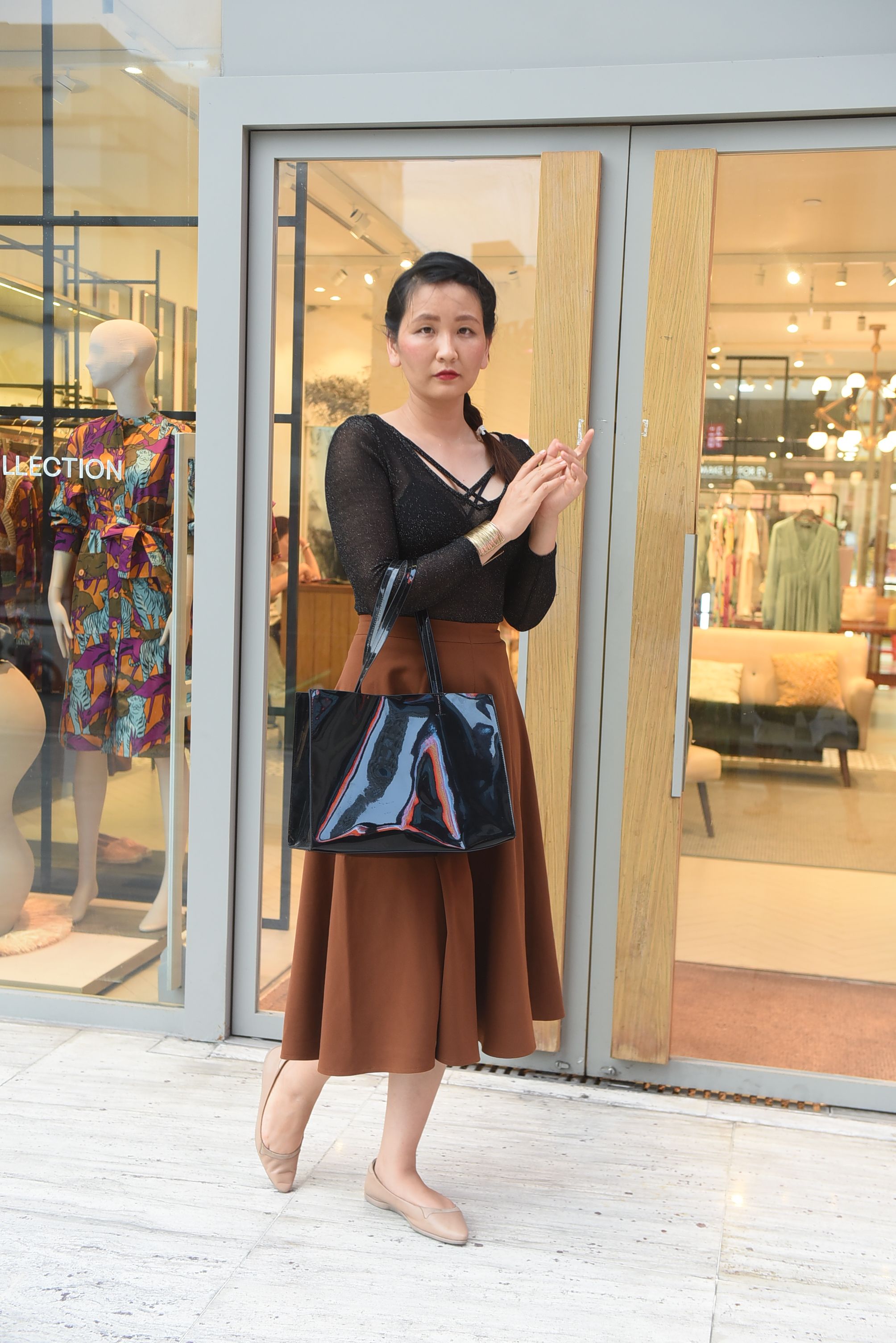 Fashionable woman standing outside a modern store, showcasing urban style. - Understanding Different Types of Handbags and Their Uses