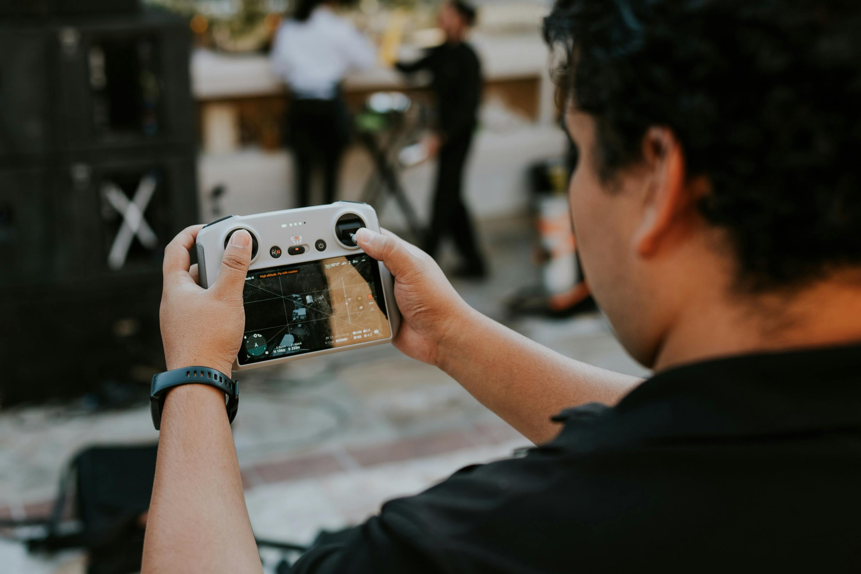 Free A man with short hair operating a drone controller at an outdoor event, focused on the screen. Stock Photo