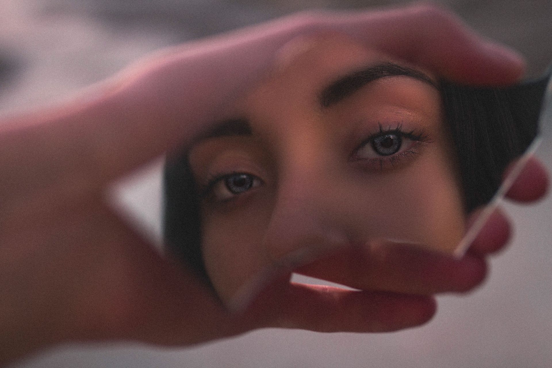 Artistic close-up of person's eyes reflected in a broken mirror, creating an intimate and mysterious feel.