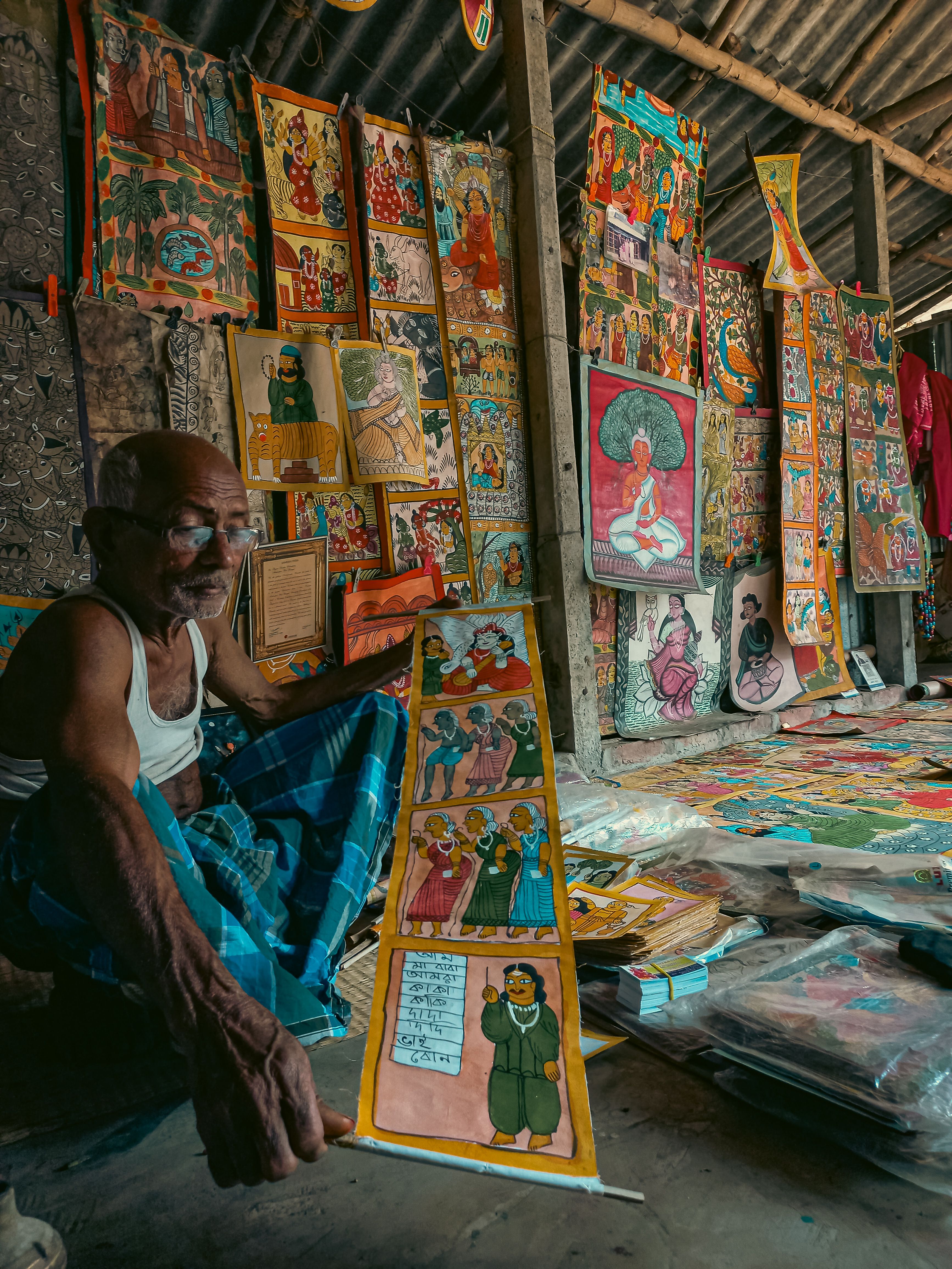 A local vendor displaying vibrant handmade paintings at a street shop in Midnapore, India.