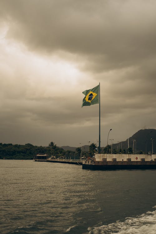 A flag flying over a pier with a cloudy sky