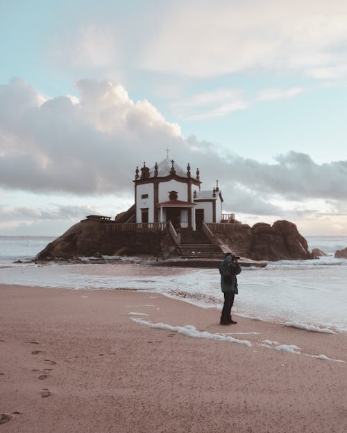 免费 男子站在圆顶大楼附近的海滩 素材图片