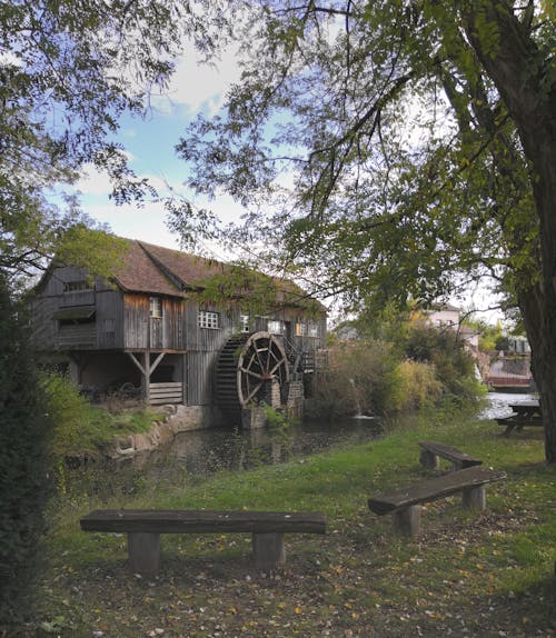 A wooden bench sits in front of a water wheel