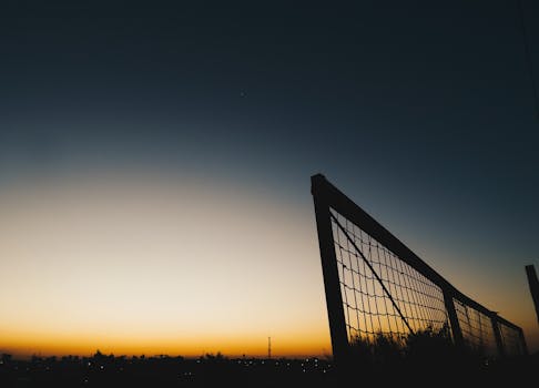 宁静的日落场景在户外拍摄，天空晴朗，映衬着栅栏的轮廓