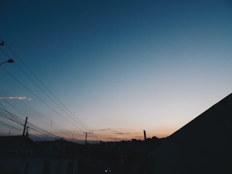 美丽的电线轮廓映衬在戏剧性的日落天空下，营造出宁静的夜晚场景