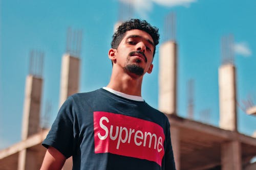 Hombre Vestido Con Camiseta Suprema Negra Y Roja Junto Al Edificio Construido