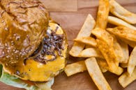 木板上放着令人垂涎欲滴的芝士汉堡，配着焦糖洋葱和酥脆的薯条