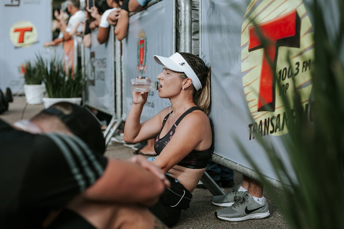 Woman in Black Crop Top Sitting and  Drinking Water