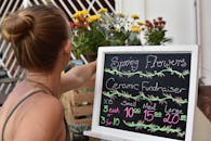 一名妇女在陶瓷筹款活动中插花，花束由春天的花朵组成，并附有定价标志