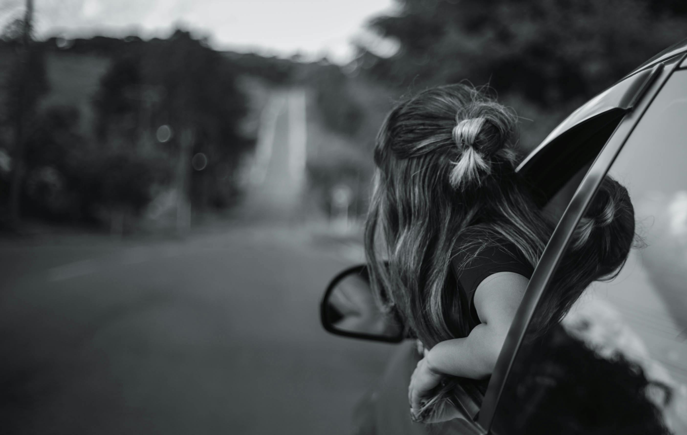 一张黑白照片里，孩子在公路旅行中从车窗欣赏风景