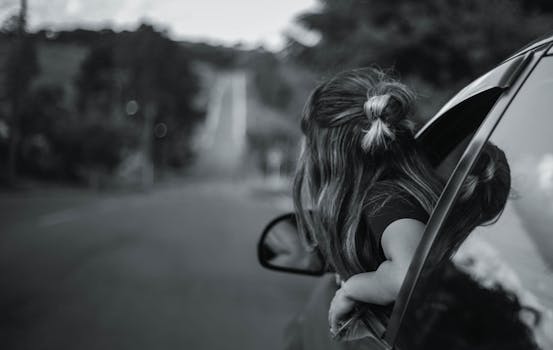 一张黑白照片里，孩子在公路旅行中从车窗欣赏风景