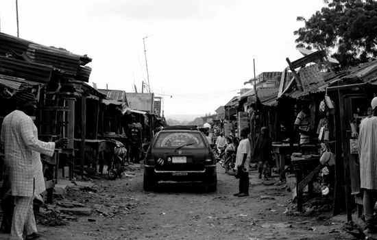 Bustling street market in Kaduna, Nigeria with vendors and customers, captured in black and white.