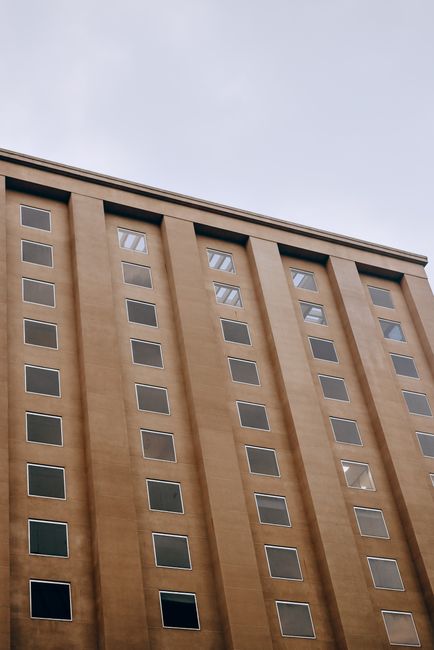 Contemporary building facade featuring glass windows and geometric design in an urban setting.