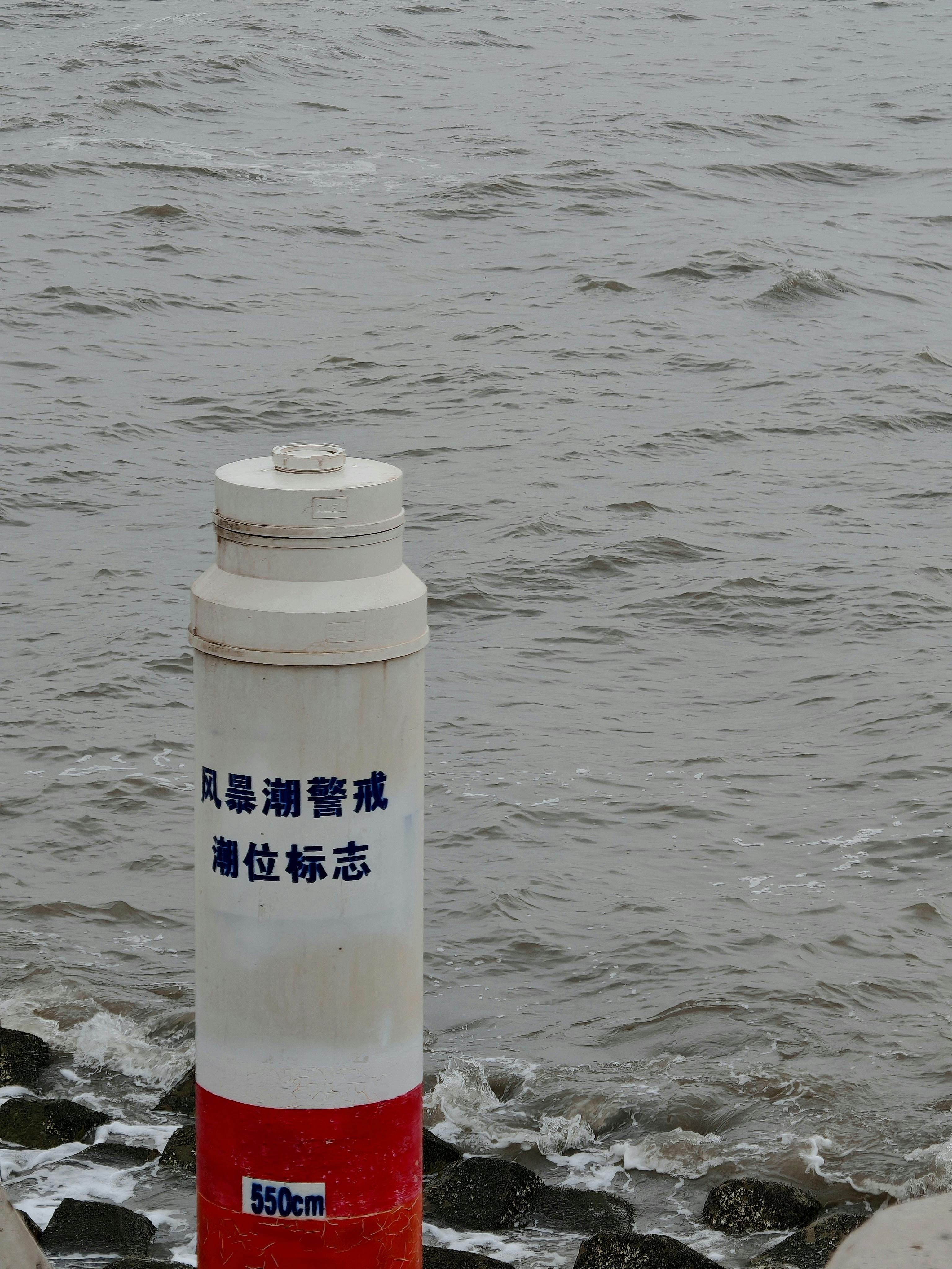 A coastal navigation marker against the sea backdrop with tide warning text.