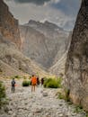 People walking through a narrow canyon with mountains in the background