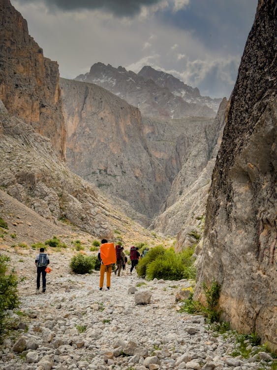 People walking through a narrow canyon with mountains in the background