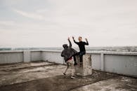 Two Men Going to High Five on Top of Building