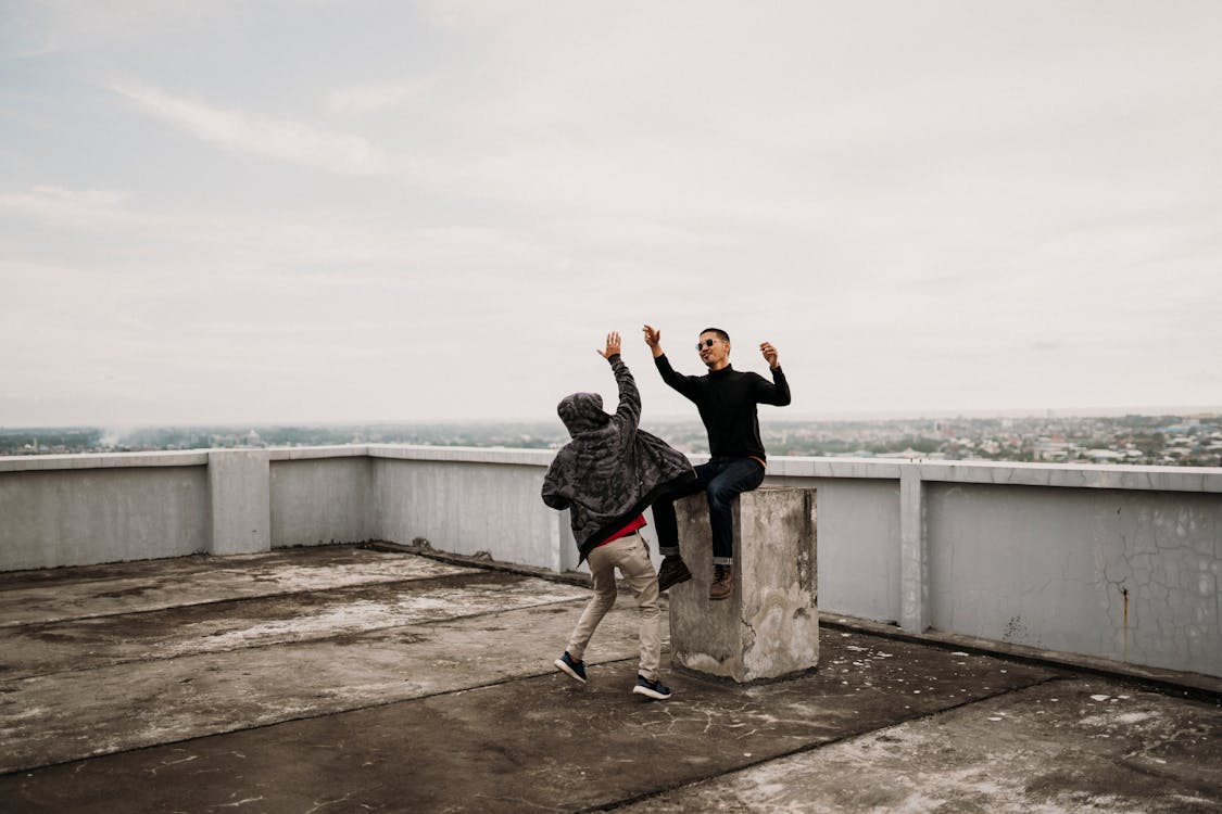 Two Men Going to High Five on Top of Building