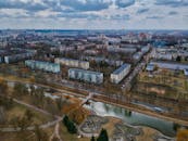 从无人机鸟瞰明斯克的城市景观，可见多云天空下的城市建筑、河流与公园绿地