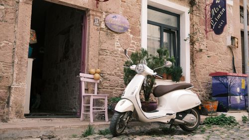 Free A quaint street view featuring a charming Vespa scooter parked outside a rustic building. Stock Photo