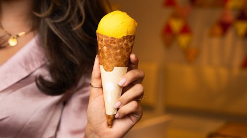A woman holding an ice cream cone with a yellow filling