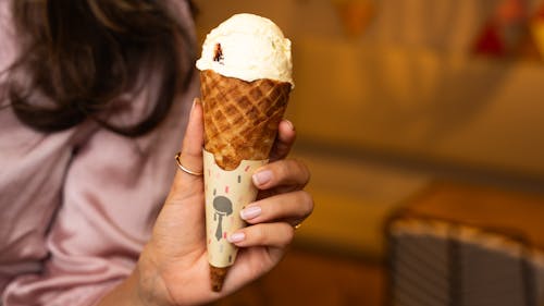 A woman holding an ice cream cone in her hand