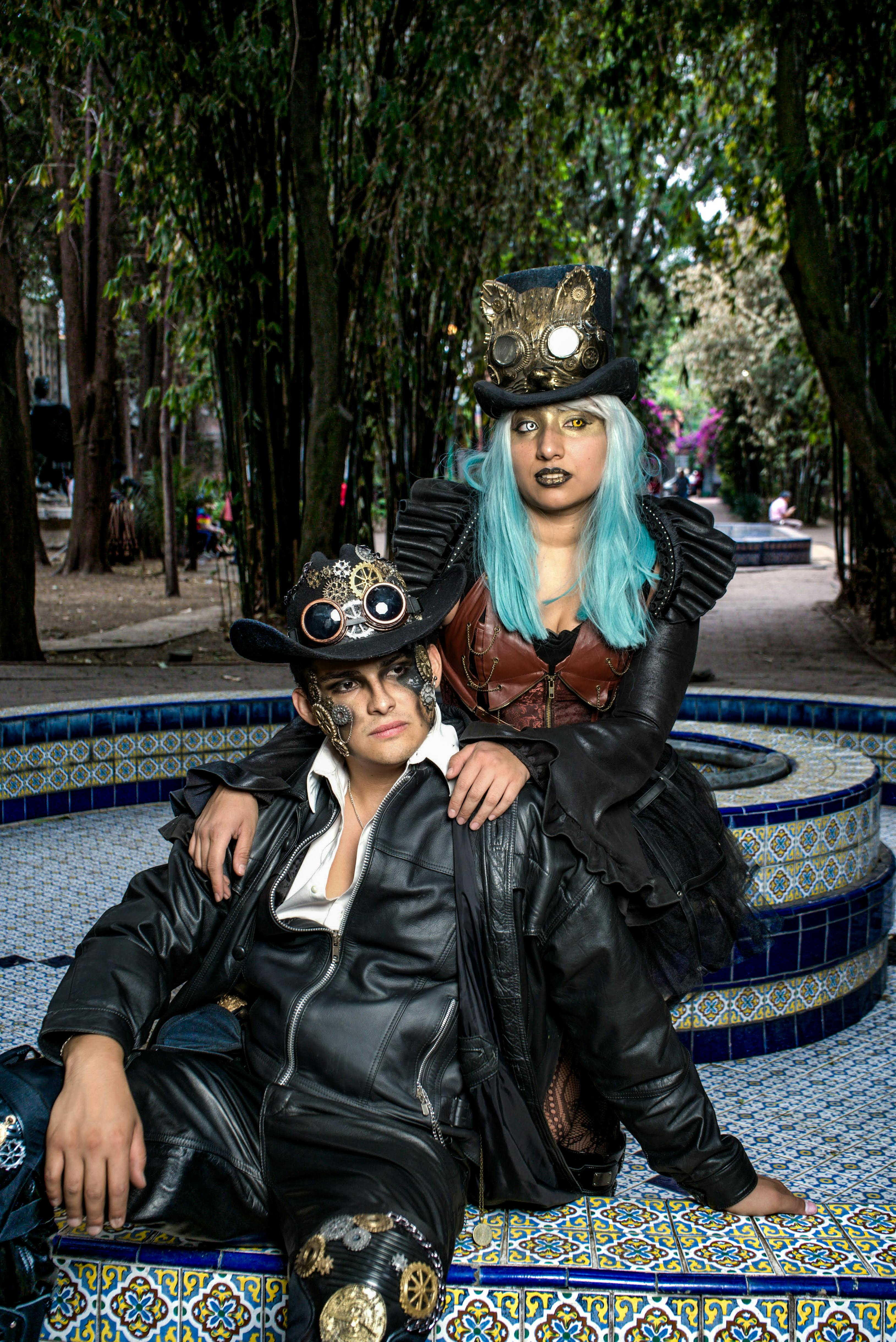 two steampunk cosplayers sitting on a fountain wall